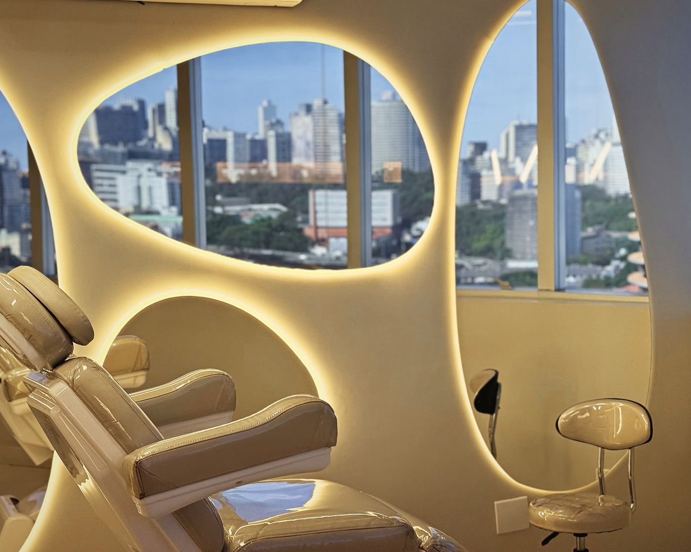 Sala de atendimento com janelas ovais iluminadas e vista para a cidade